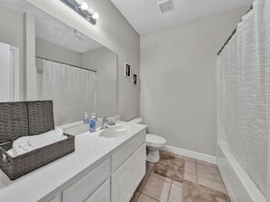 A bathroom with a white vanity, a large mirror, a toilet, and a shower curtain. - Modern & Cozy 3BR Home Close to Lake (Grand Prairie)