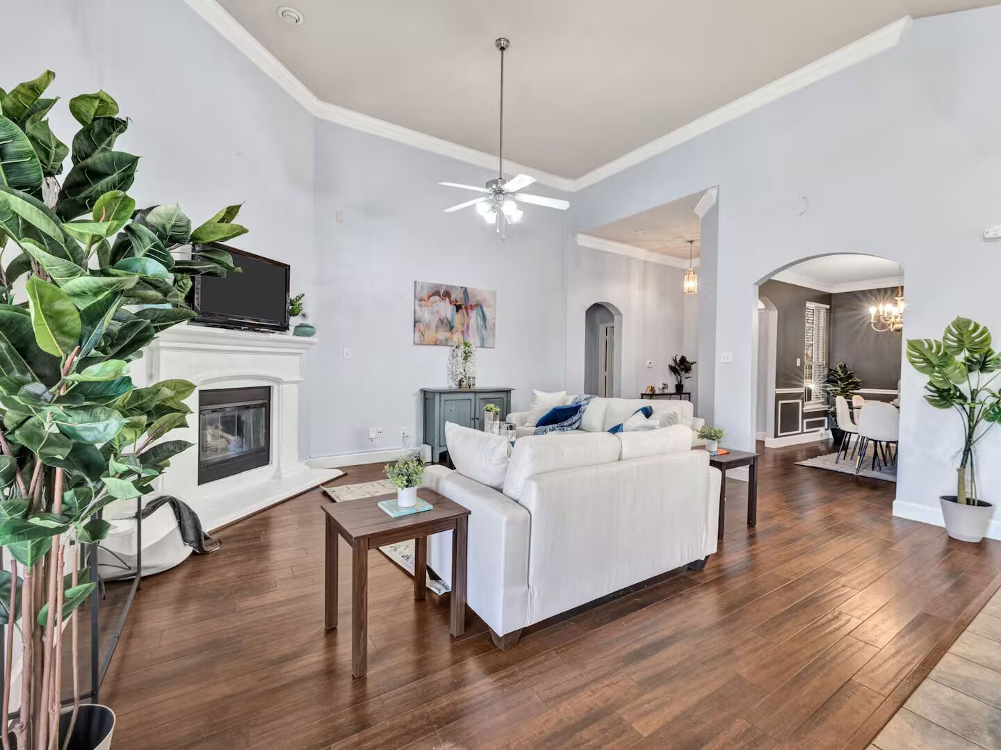 A spacious living room with a fireplace, a sofa, a coffee table, and a dining area with a chandelier.