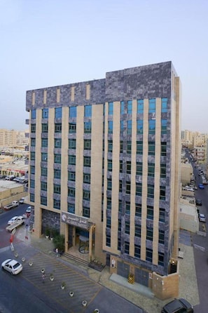 A multi-story hotel with a central entrance, a parking lot, and a view of the surrounding urban area. - Al Aseel Hotel Doha (Doha)