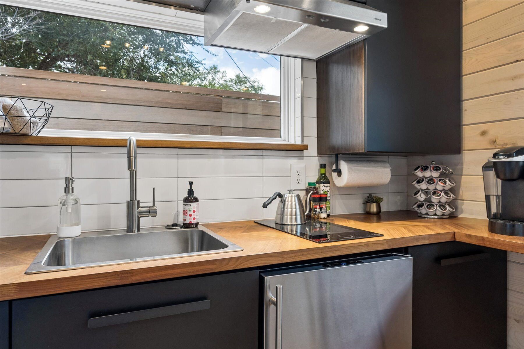 A modern kitchen with a stainless steel sink, a kettle, and a coffee machine.