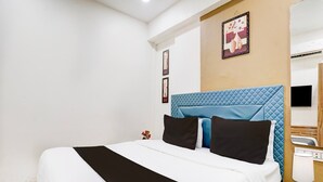 A hotel room with a bed, a bedside table, a nightstand, a lamp, and a wall-mounted TV. - Classic Hotel Signature (Surat)
