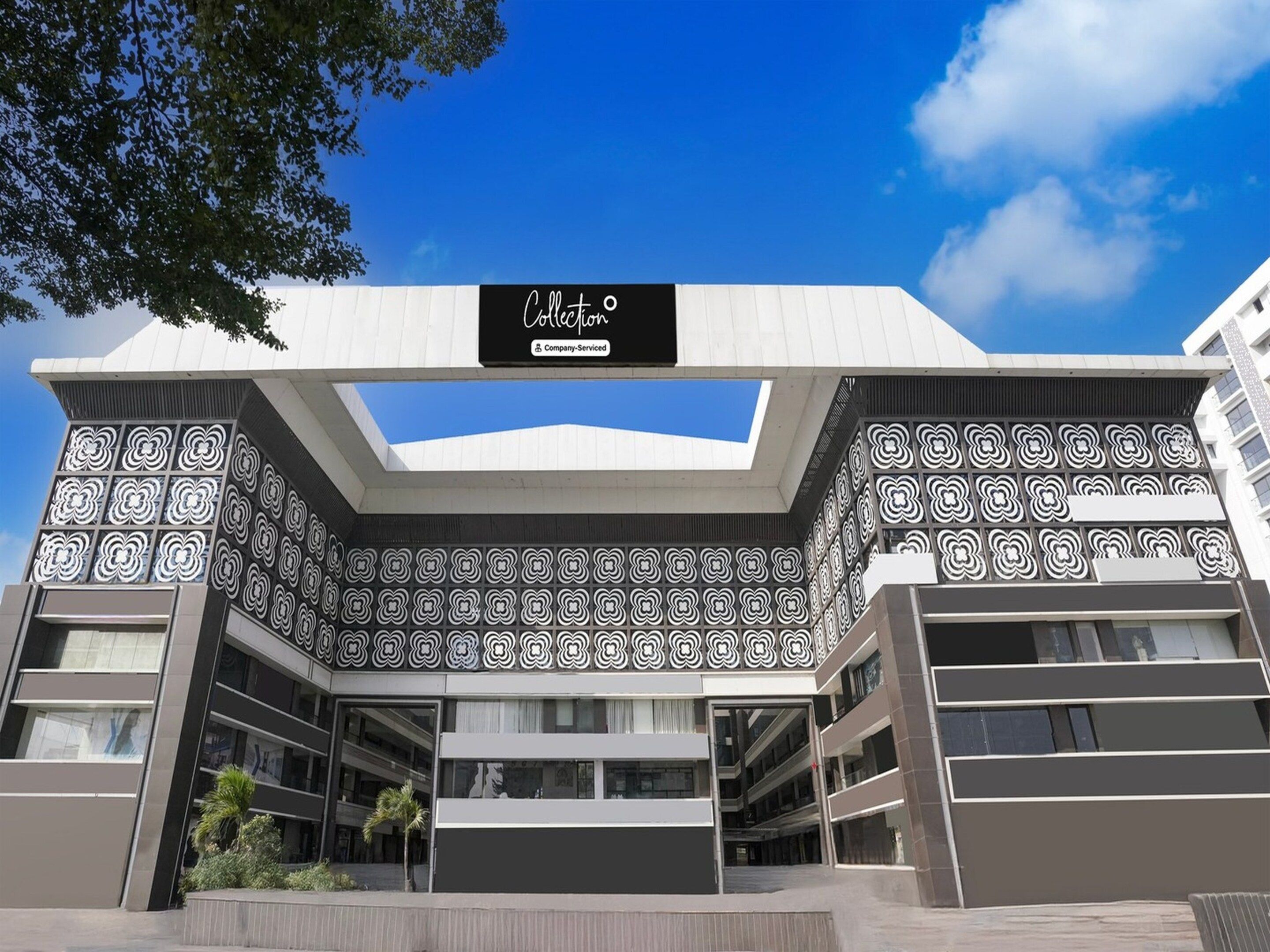 A modern building with a geometric facade, a company-serviced sign, and a clear sky.