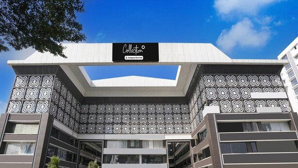 A modern building with a geometric facade, a company-serviced sign, and a clear sky. - Classic Hotel Signature (Surat)