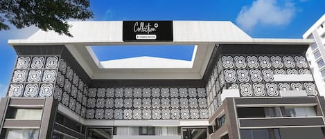 A modern building with a geometric facade, a company-serviced sign, and a clear sky.