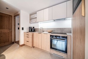 Een moderne keuken met houten kastjes, een inbouwoven en een koffiezetapparaat.