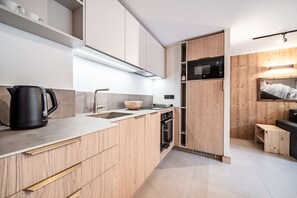 Una cuina moderna amb armaris de fusta, forn de sobre i microones.