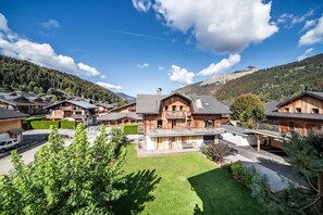 A traditional chalet-style building with a wooden exterior, surrounded by a well-maintained lawn and a parking area. - ARKOS 202: Beautiful two-bedroom apartment for 4–5 guests in the heart of Morzine (MORZINE)