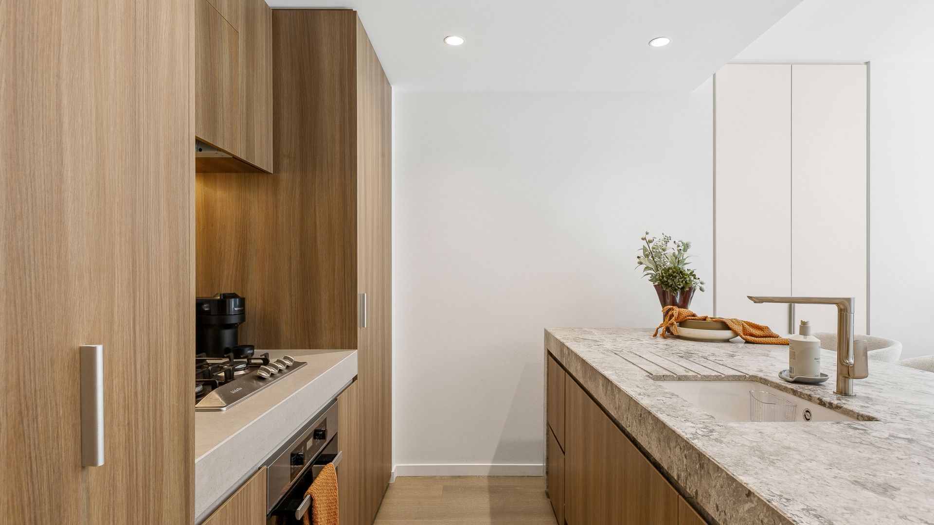 Une cuisine moderne avec des meubles en bois, un plan de travail en marbre et une cuisinière intégrée.