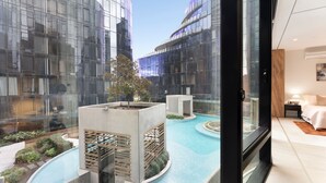 Quarto de hotel moderno com vista para uma piscina e edifícios circundantes.