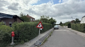 Una calle residencial con una señal de obra, un hidrante y una señal de estacionamiento.