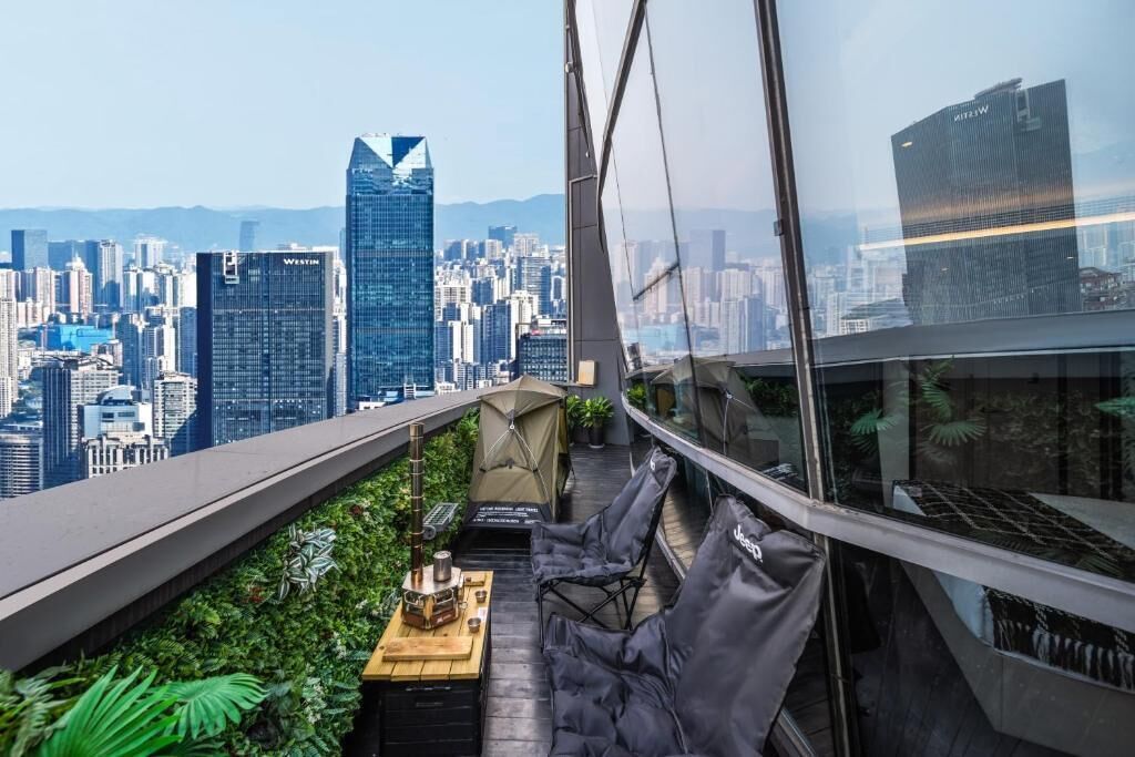 A rooftop terrace with a city view, a table with a grill, and seating.