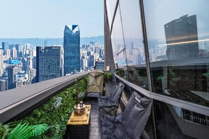 A rooftop terrace with a city view, a table with a grill, and seating. - Kongshang  River view Hotel (Chongqing)