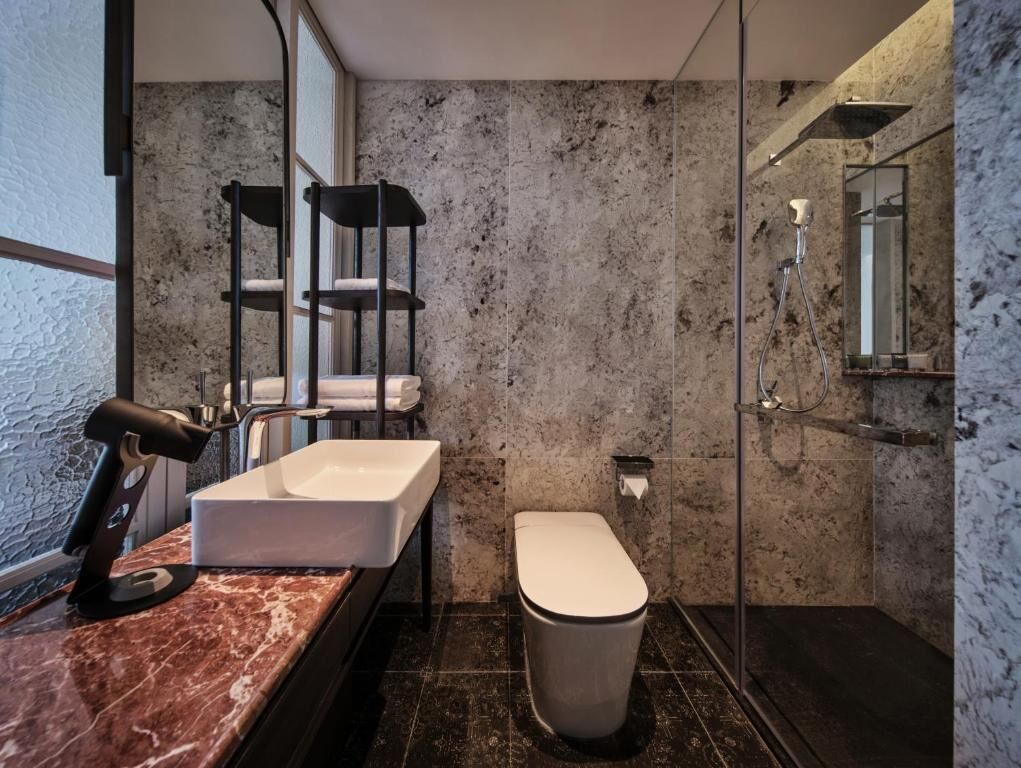 Un bagno moderno con lavabo in marmo, un water e cabina doccia in vetro.