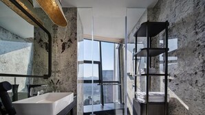 Casa de banho moderna com uma janela grande, uma pia branca e uma estante preta.
