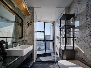 Un baño moderno con un ventanal grande, un lavabo blanco y una estantería negra.