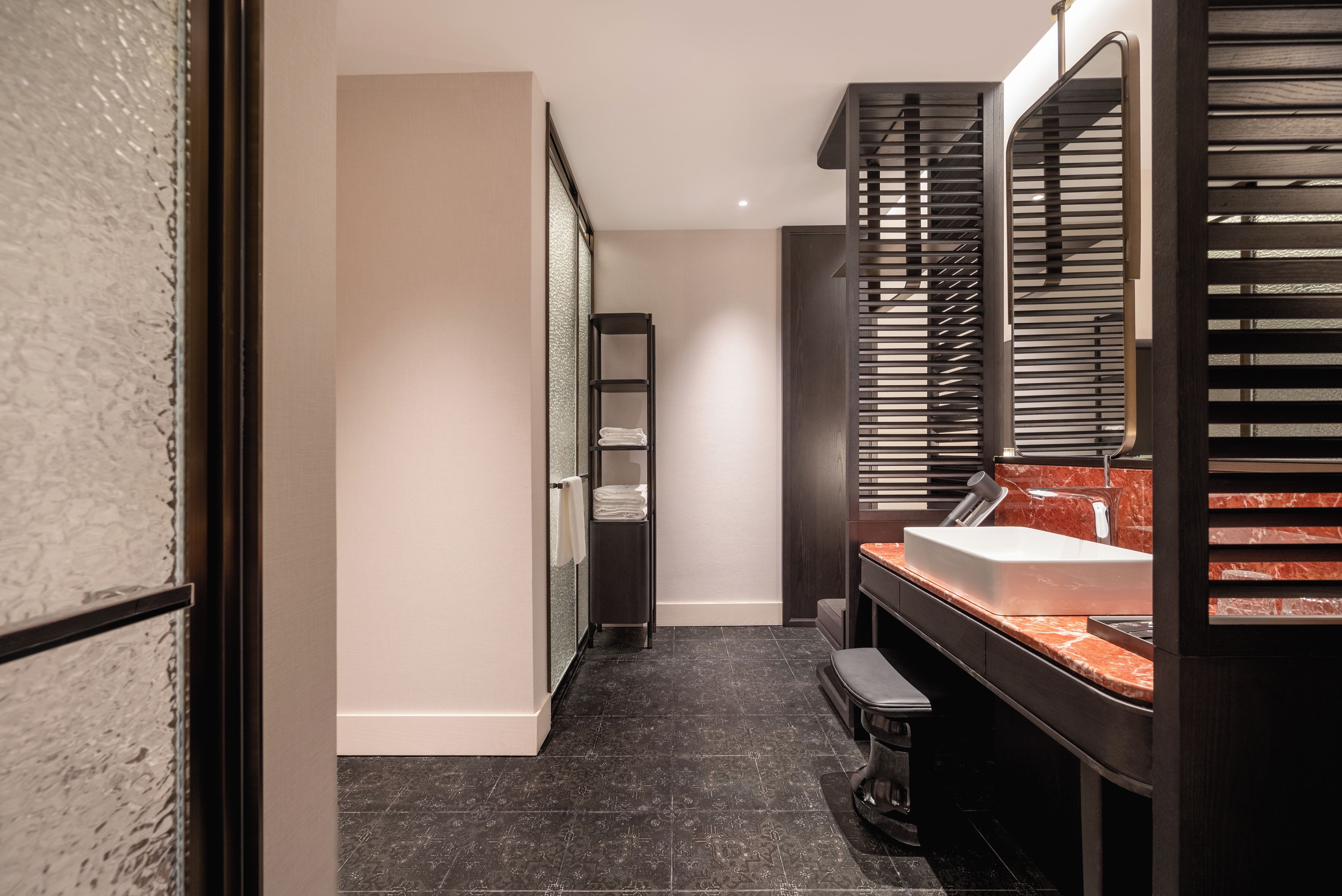 A modern bathroom with a marble sink, dark wood vanity, and a large mirror with blinds.