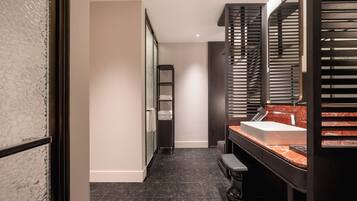 A modern bathroom with a marble sink, dark wood vanity, and a large mirror with blinds.
