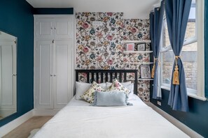 A bedroom with a bed, a wardrobe, a window with curtains, and a floral wallpaper. - Fulham s Best-kept Secret 2 Bed Walled Garden (London)