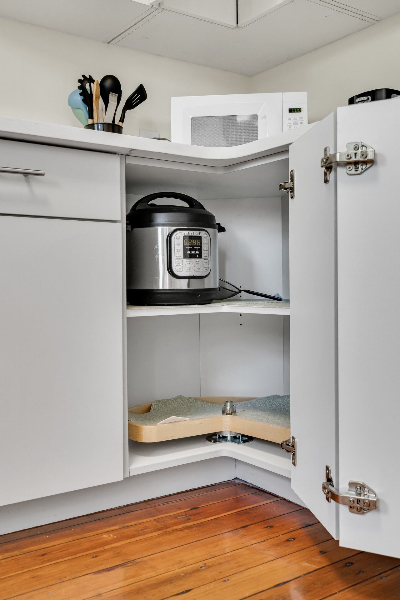 Una cocina compacta con microondas, olla de cocción Instant Pot y encimera de madera.