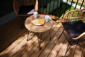 A wicker table with a plate of food and two cups on a wooden deck. - Cozy Mid-Century Modern Hideaway (Durham)