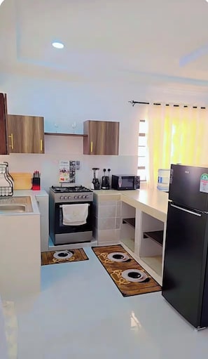 Eine moderne Küche mit Gasherd, Mikrowelle und Kühlschrank.