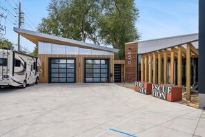 A modern building with two garage doors, a fire station sign, and a recreational vehicle parked in front. - Modern 1BR: Reimagined Firehouse (Denver)