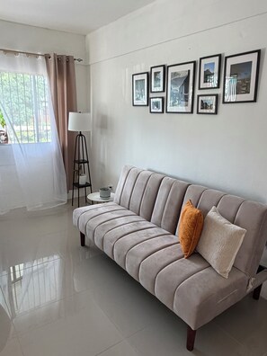 Una sala de estar moderna con un sofá, una lámpara y cuadros en la pared.