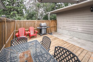 An outdoor patio with a wooden deck, a grill, red Adirondack chairs, and a table with metal chairs. - airport aside, park &shopping around Cozy 5 beds comfort home (Calgary)