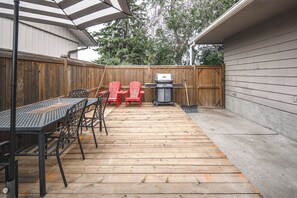 A wooden deck with a table and chairs, a grill, and a trash can. - airport aside, park &shopping around Cozy 5 beds comfort home (Calgary)