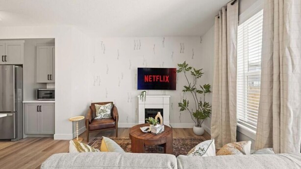 Ein Wohnzimmer mit Kamin, einer Couch, einem Couchtisch und einem an der Wand befestigten Fernseher.