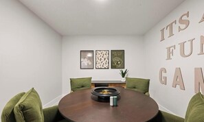Ein Zimmer mit einem runden Tisch, grünen Kissen und gerahmten Bildern an der Wand.