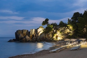 A beach with rocky formations, a row of sun loungers, and umbrellas. - Zeus Eleva Ajul, a Registry Collection Hotel (Kassandra)