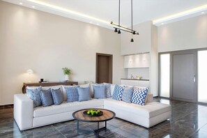 A modern living room with a sectional sofa, a coffee table, and a pendant light fixture.