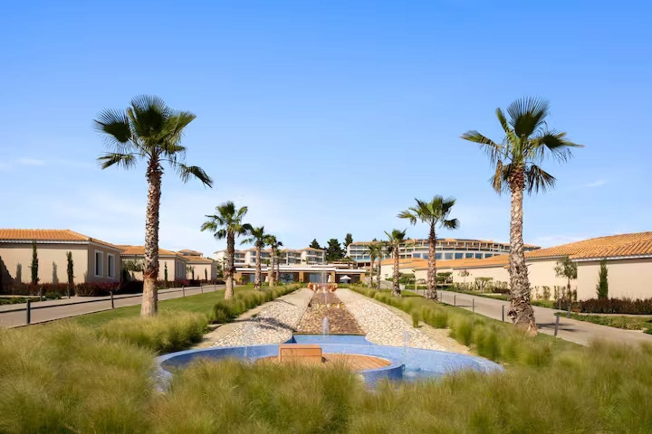 A hotel with a central courtyard, palm trees, and a pool.