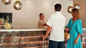 A reception area with a marble counter, hanging spherical light fixtures, and a decorative plant.
