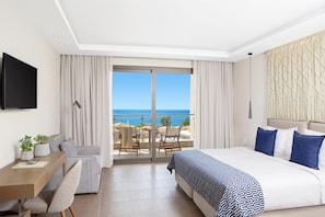 A hotel room with a bed, a desk, a chair, a TV, and a balcony with a view of the sea. - Zeus Eleva Ajul, a Registry Collection Hotel (Kassandra)