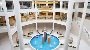 A multi-level atrium with a central pool, glass railings, and modern furnishings.