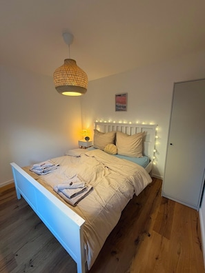 Een slaapkamer met een bed, een bedlampje en een hanglamp.