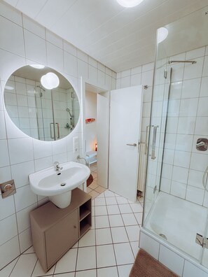 Een moderne badkamer met een wit wastafelmeubel, spiegel en een douchecabine met glazen wanden.
