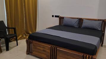A bedroom with a wooden bed, a chair, and a curtain.