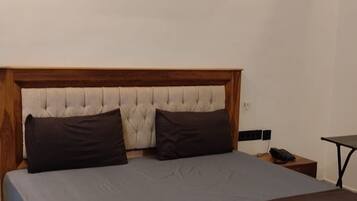 Un dormitorio con una cama, una mesita de noche, un teléfono y un equipo de aire acondicionado en la pared.