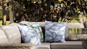 A sectional sofa with patterned cushions and a wicker chair.