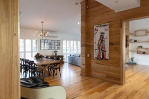 Ein geräumiger Wohnbereich mit Holzboden, einem Esstisch mit Stühlen, einer Couch und einem Gemälde an der Wand.