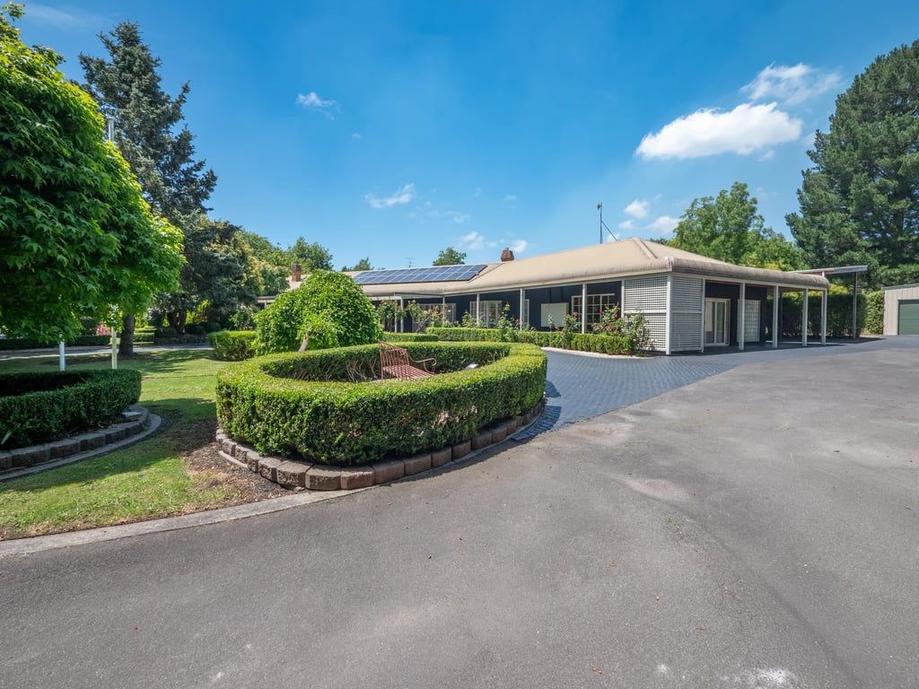 A building with a covered outdoor area, a paved driveway, and well-maintained landscaping.