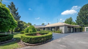 A building with a covered outdoor area, a paved driveway, and well-maintained landscaping.