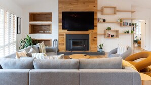 A modern living room with a fireplace, a flat-screen TV, and built-in shelving.