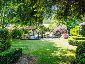 Ein Garten mit einem Pavillon, einer Brücke und verschiedenen Pflanzen.
