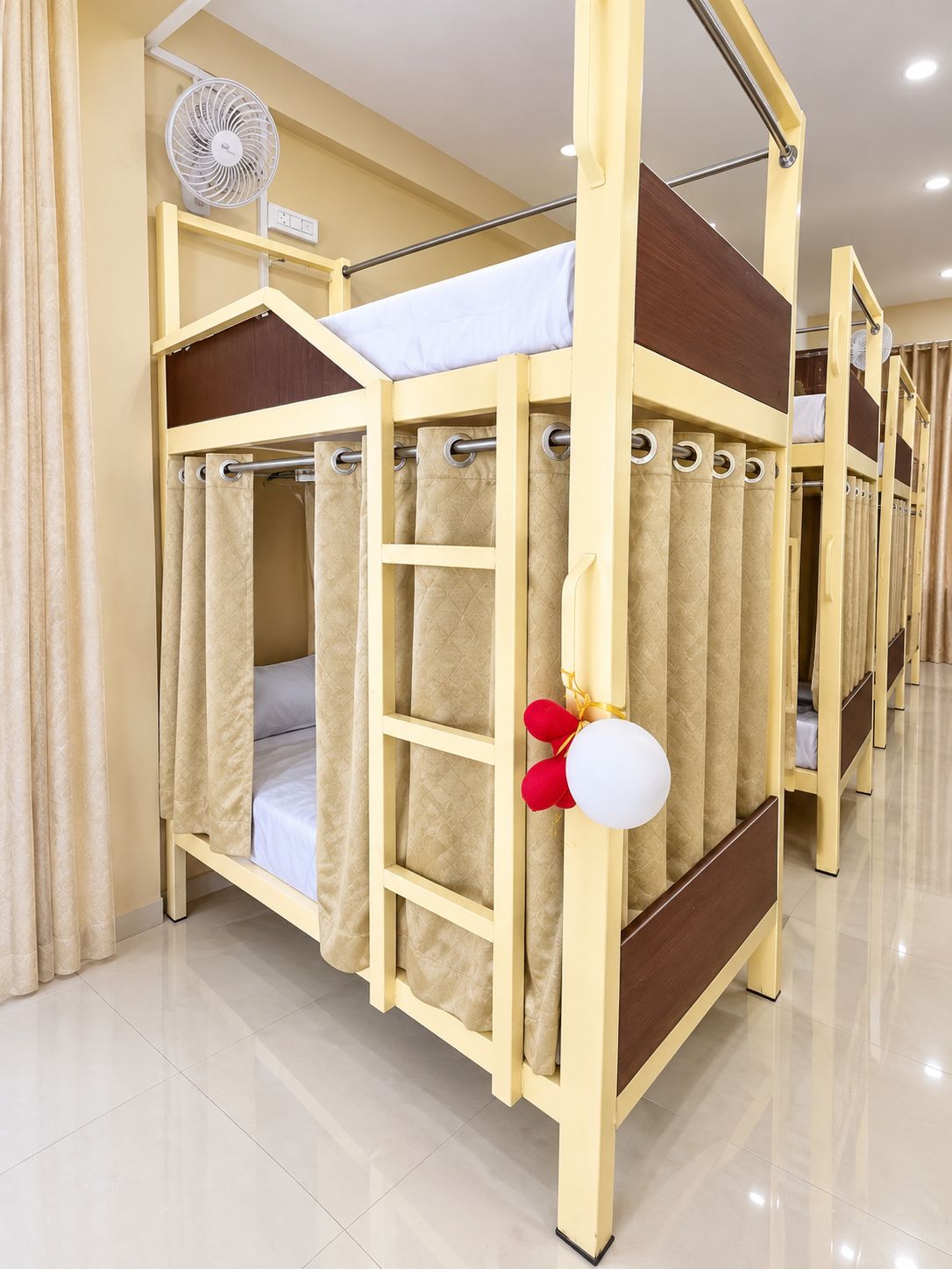 Una cama litera con cortina, un ventilador y una decoración con globo.