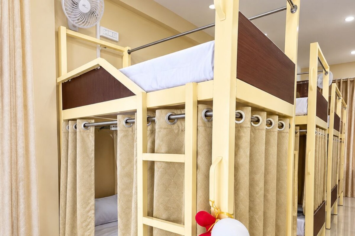 Una cama litera con cortina, un ventilador y una decoración con globo.