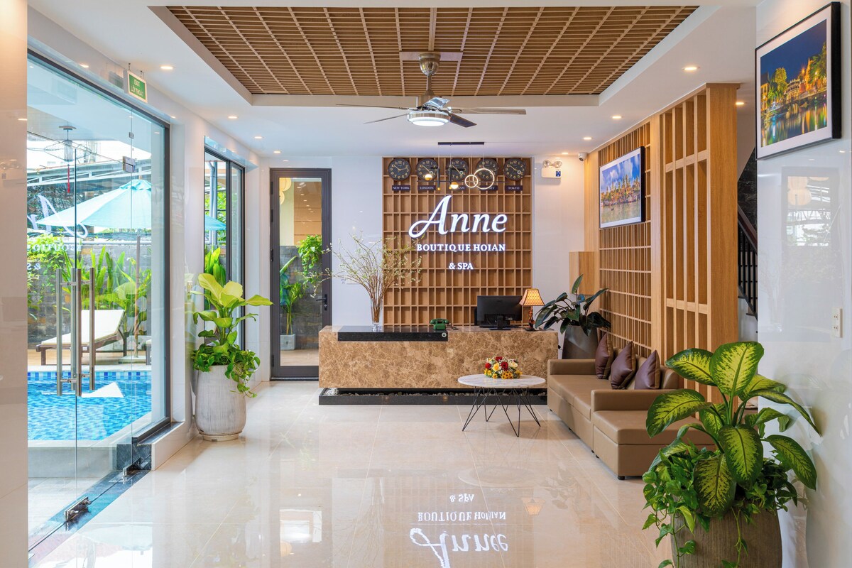 Un vestíbulo de hotel con recepción, zona de piscina y área de descanso con plantas.